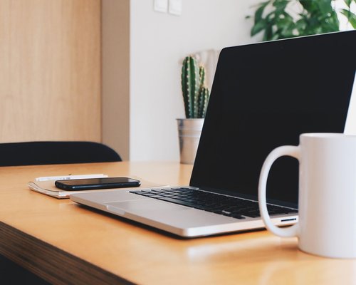 A modern office desk in Bucharest with a laptop and a notepad