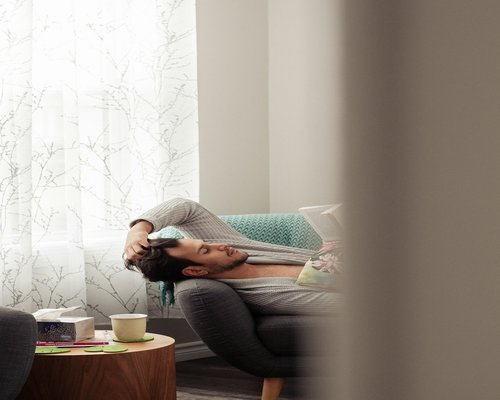 Person relaxing in a bright, modern living room with a cup of tea